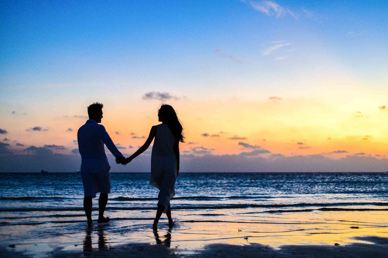 Couple marchant main dans la main au coucher du soleil, symbole de solidarité et de transmission patrimoniale dans le cadre d’une donation entre époux.