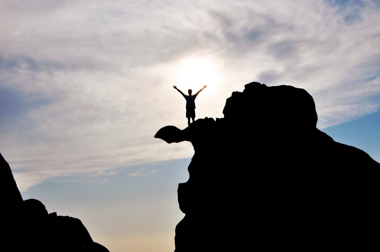 Silhouette d’une personne debout sur un rocher face à l’horizon, symbolisant la liberté et les opportunités d’investissement offertes par un CTO pour expatriés.